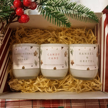 Load image into Gallery viewer, Three candles labeled 'Frankincense & Myrrh', 'Candy Cane', and 'Hansel & Gretel' in a decorative box with Christmas elements.