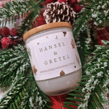 Load image into Gallery viewer, Candle with a wooden lid labeled 'Hansel & Gretel' surrounded by Christmas decorations.