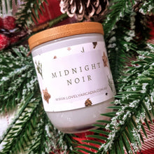 Load image into Gallery viewer, Candle labeled 'Midnight Noir' with a wooden lid on a Christmas-themed background