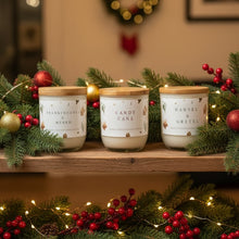 Load image into Gallery viewer, Three candles with wooden lids on a table with a decorative background
