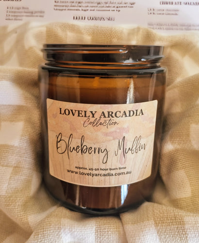 Candle jar with 'Lovely Arcadia' label on a checkered fabric background. Blueberry Muffin