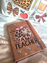 Load image into Gallery viewer, Notebook with decorative cover featuring &#39;Teacher&#39; text and leopard print design on a white fabric background.
