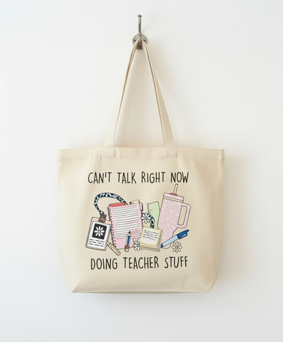 Beige tote bag with teacher-themed design and text on a checkered fabric background